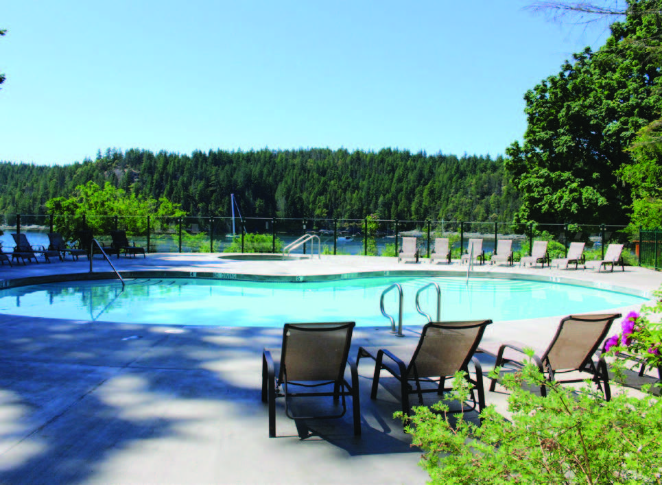 Several chairs surround an in-ground swimming pool overlooking the ocean.